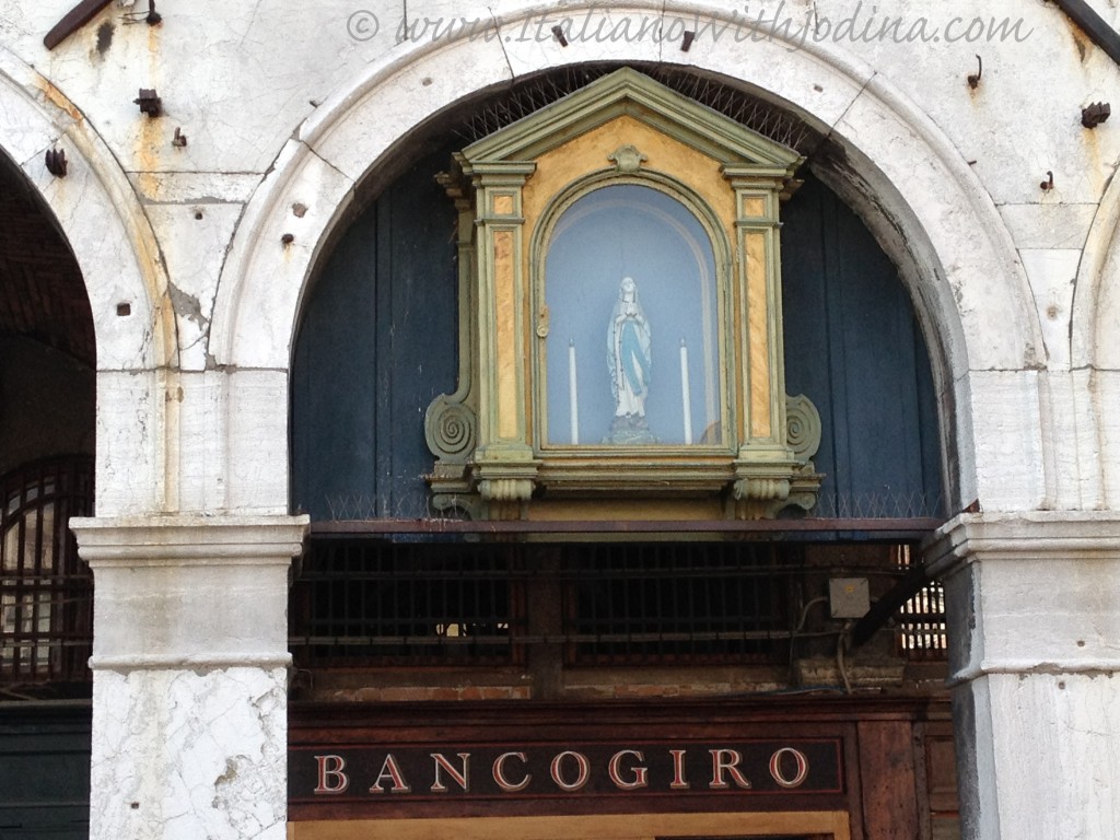 sign in venice, italy, for a bank with the vergin mary in a glass disply case above it