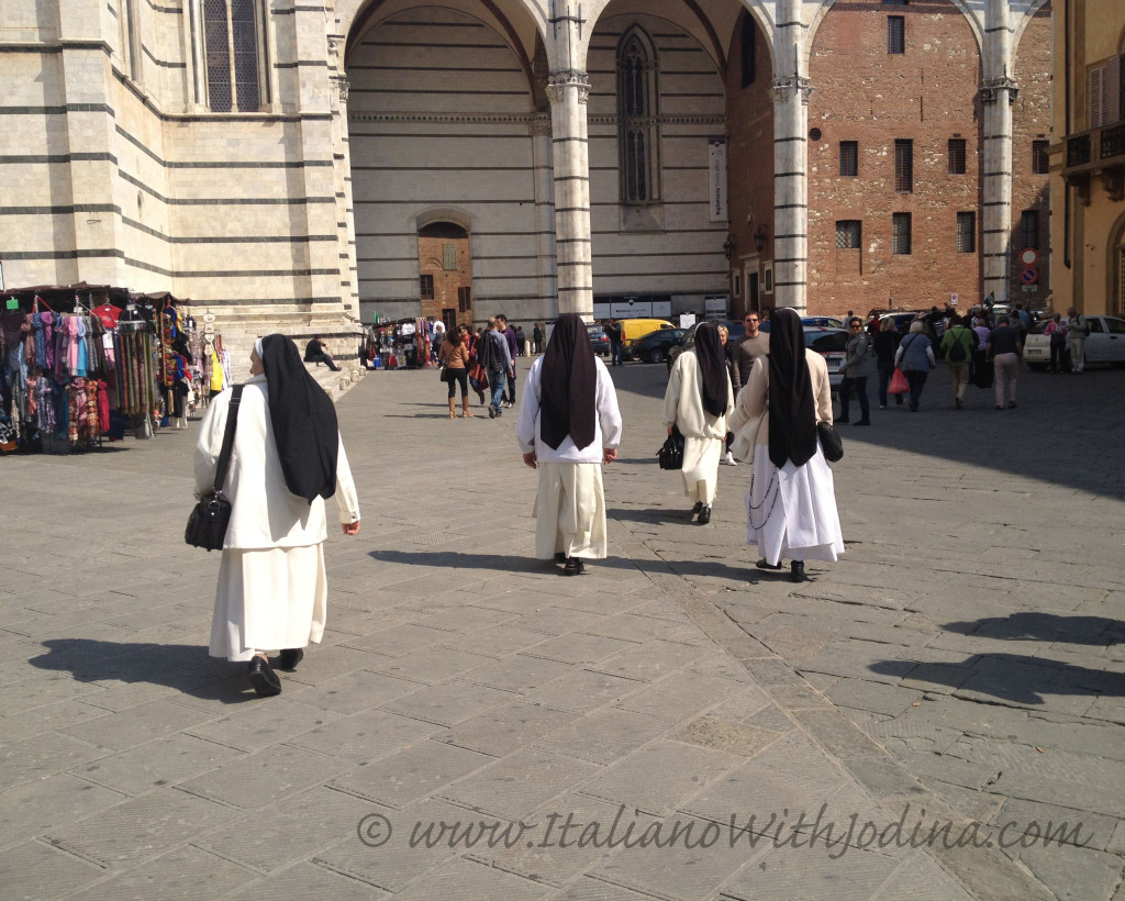 nuns walking into distance piazza del duomo siena